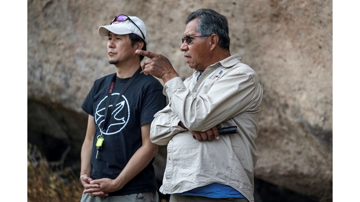 Two men standing in a cave, one is pointing