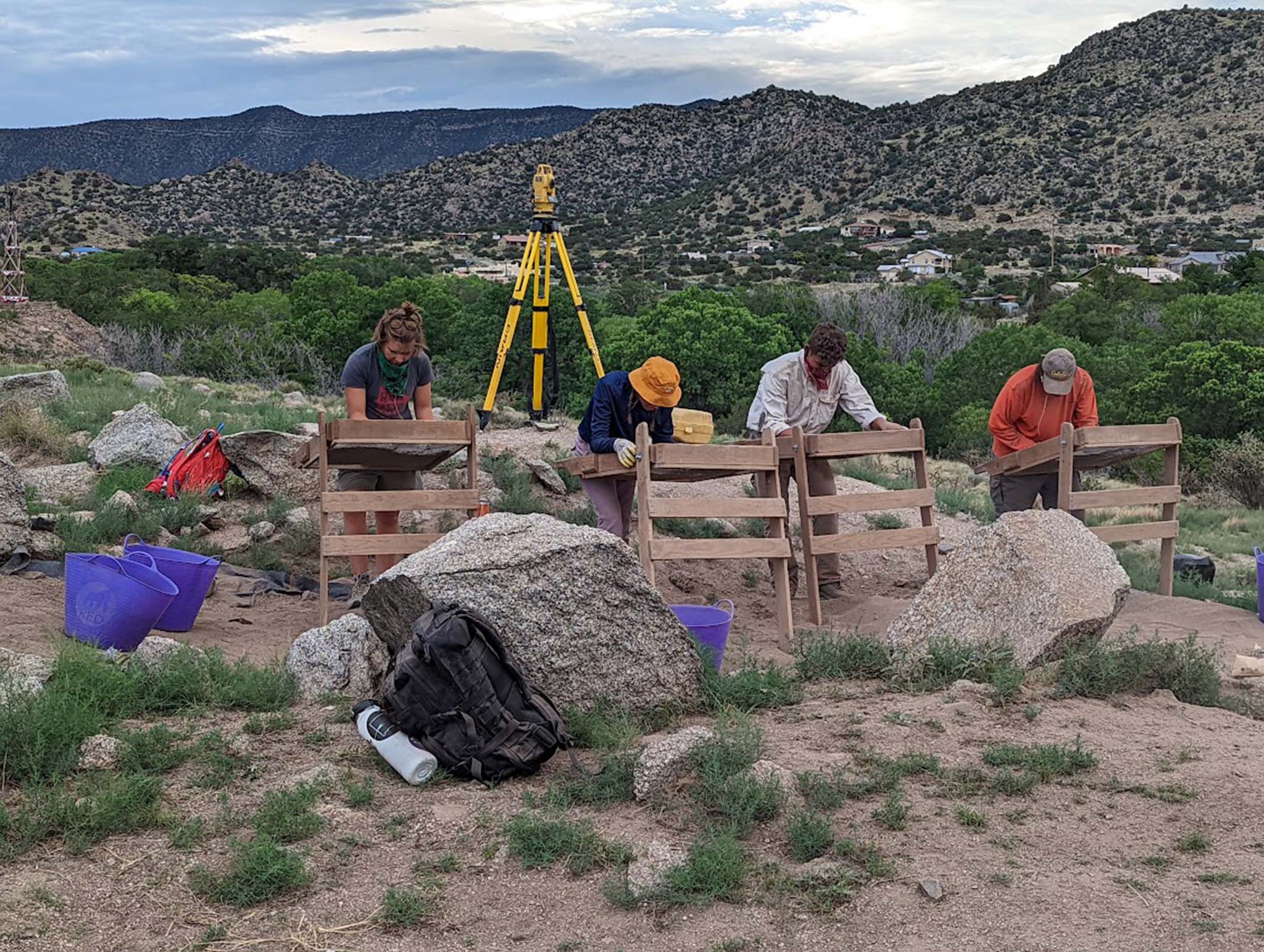 Four people screening sediment